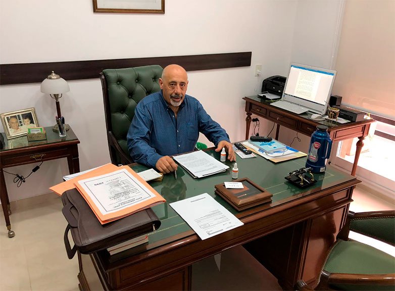 Dr. Raúl Abraham en su estudio jurídico, sentado en su escritorio.